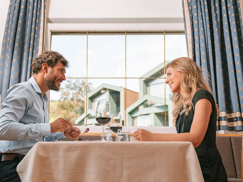Paar beim Abendessen in einem gemütlichen Restaurant mit Wein und Essen