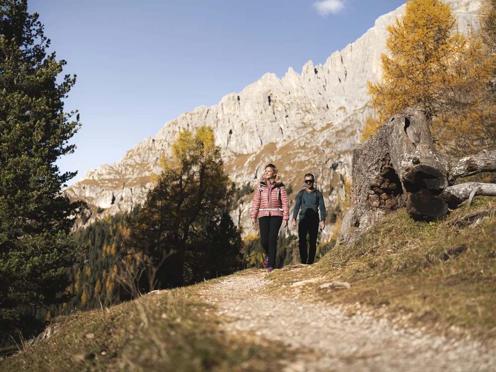 Zwei Frauen wandern auf einem Bergweg vor einer hellen Felswand
