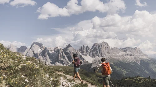 Wanderer auf Bergpfad mit Dolomiten im Hintergrund und blauem Himmel