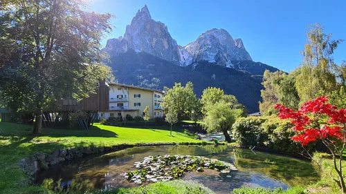 Berglandschaft mit Haus, Teich und buntem Baum im Sonnenschein