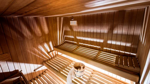 Innenansicht einer holzverkleideten Sauna mit Holzeimer und Handtuch