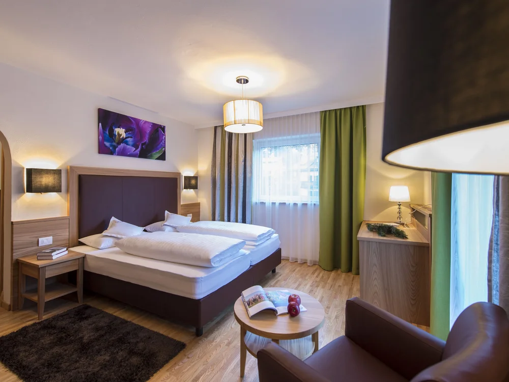 Modernes Hotelzimmer mit Doppelbett, Stuhl, Tisch und Beleuchtung