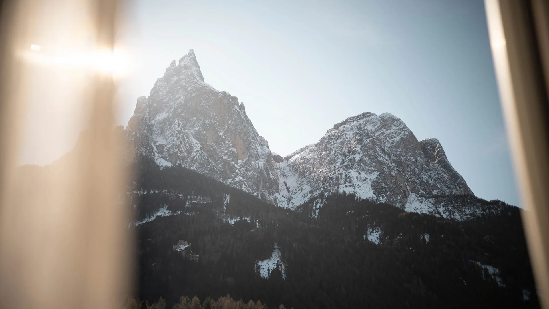 Blick auf schneebedeckte Bergspitzen durch ein Fenster bei Sonnenaufgang
