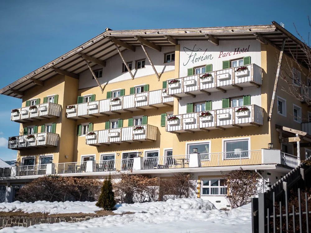 Gelbes Hotel mit Balkonen und Schnee im Vordergrund