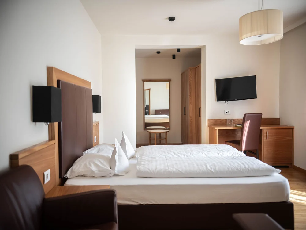 Modernes Hotelzimmer mit Doppelbett, Schreibtisch und Fernseher