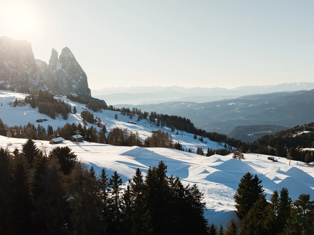 Schneebedeckte Berglandschaft mit Tannen und Felsen im Sonnenlicht