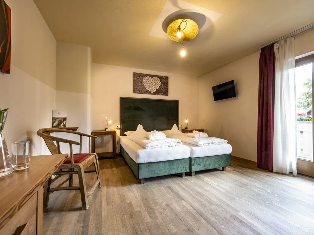 Gemütliches Schlafzimmer mit Doppelbett, Holzboden und Zugang zum Balkon