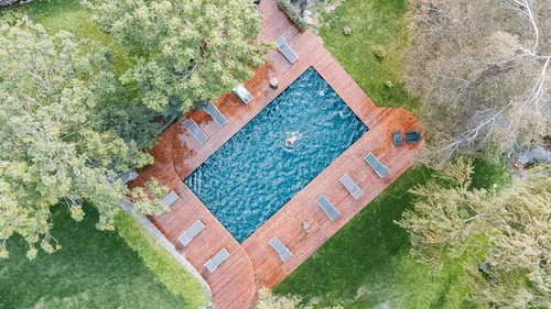 Vogelperspektive auf einen Pool mit Holzboden und einer Person im Wasser