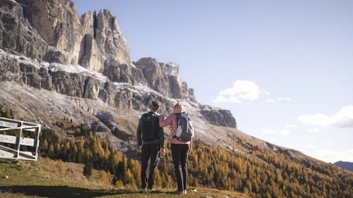 Zwei Wanderer vor einer beeindruckenden Berglandschaft mit herbstlichem Wald