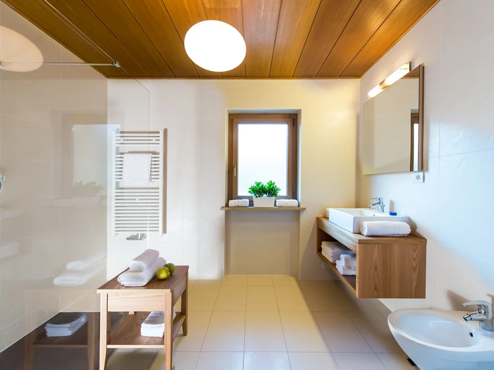 Helles Badezimmer mit Holzmöbeln und Fenster mit Pflanzen