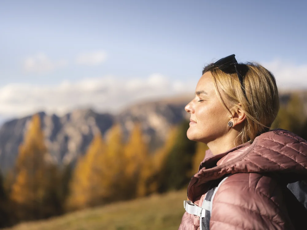 Frau mit Sonnenbrille auf dem Kopf vor herbstlicher Berglandschaft