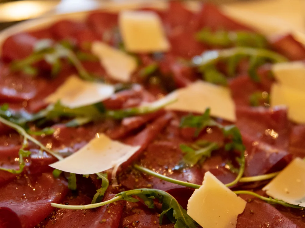 Nahaufnahme von Carpaccio mit Rucola und Parmesan auf Teller