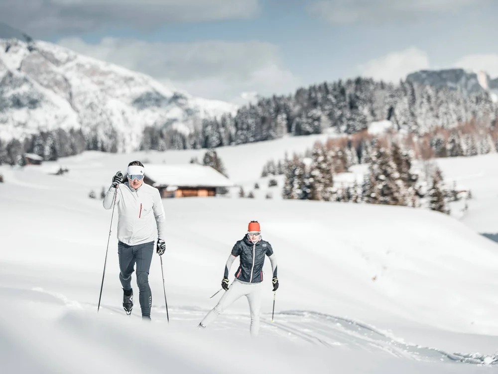 Zwei Personen beim Langlaufen in verschneiter Berglandschaft