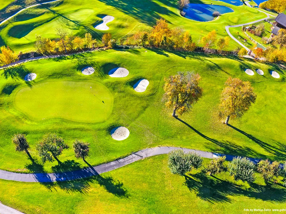 Luftaufnahme eines Golfplatzes mit Bunkern und herbstlichen Bäumen
