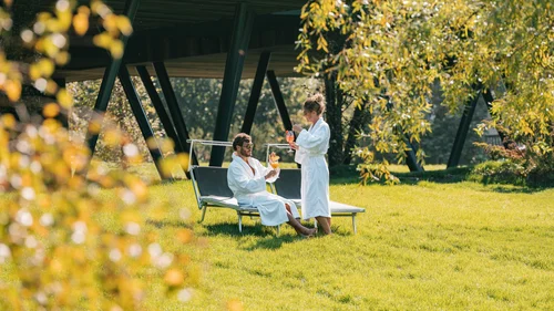 Paar in Bademänteln mit Cocktails im Garten eines modernen Hauses