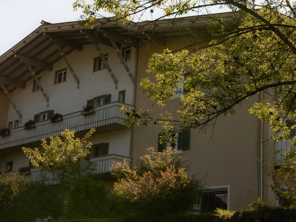 Haus mit Balkon und grünen Bäumen im Sonnenschein