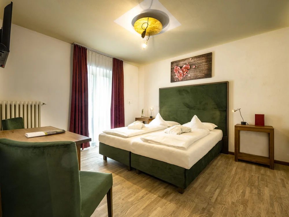 Gemütliches Hotelzimmer mit grüner Bettkopflehne und Dekoration