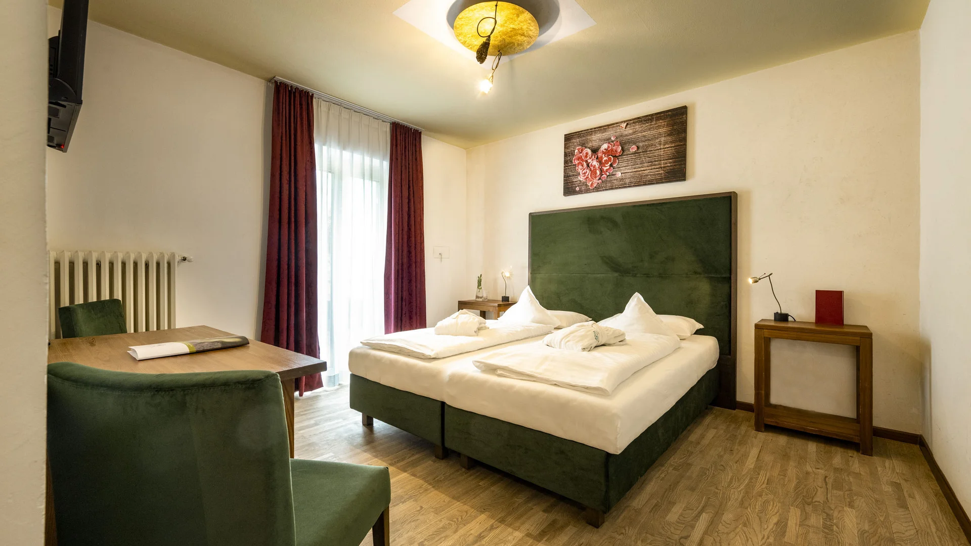 Gemütliches Hotelzimmer mit grüner Bettkopflehne und Dekoration